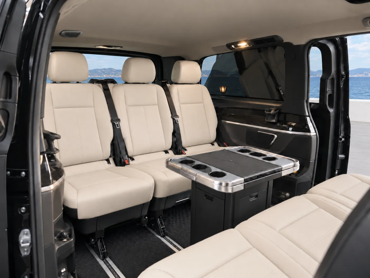 Two facing rows of three light leather passenger seats and a central table inside a Mercedes-Benz Vito