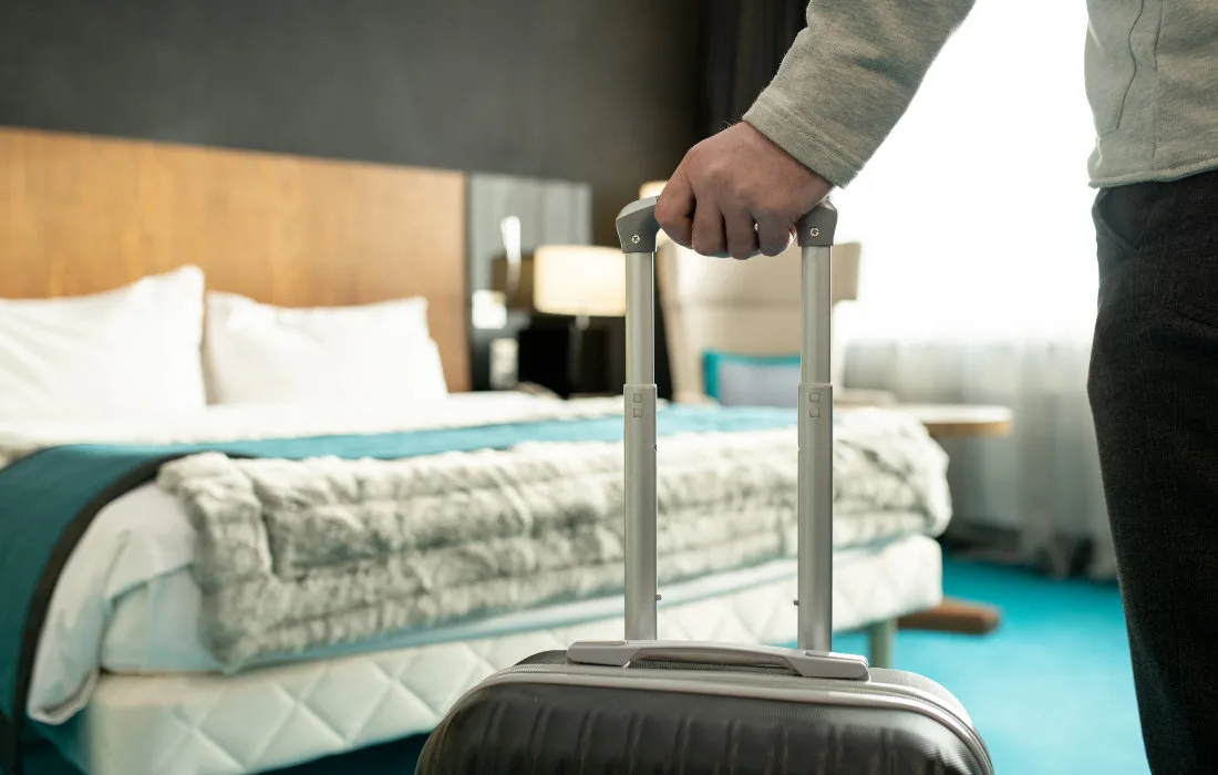 Hand of male traveler or businessman in casualwear holding by handle of his suitcase